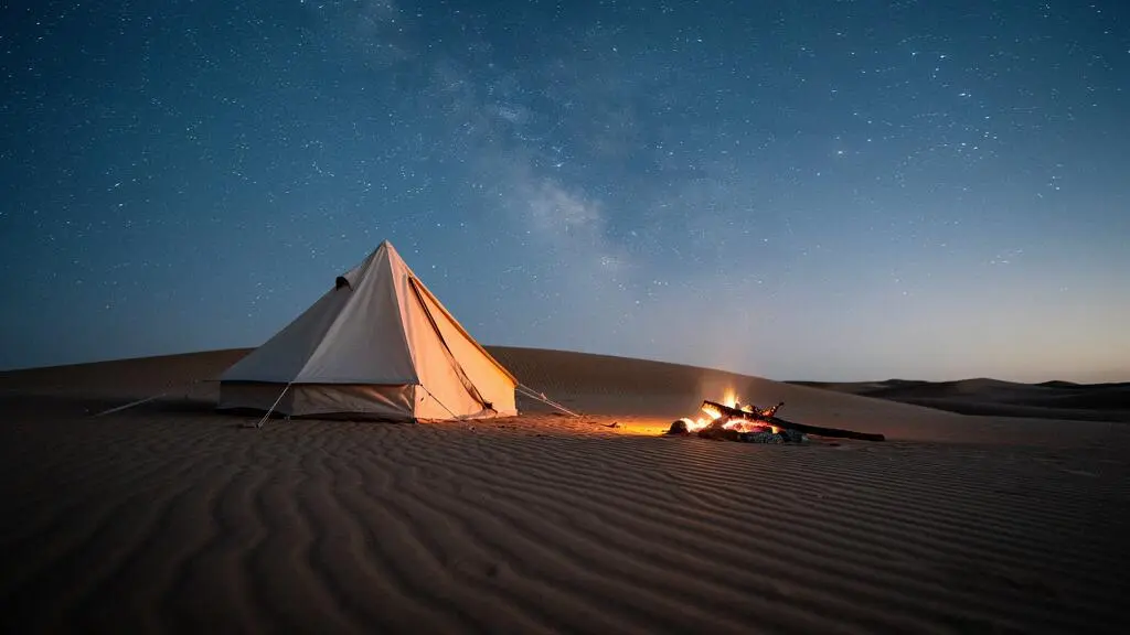 Tente de bivouac isolée au sommet d'une dune sous un ciel étoilé dans le désert