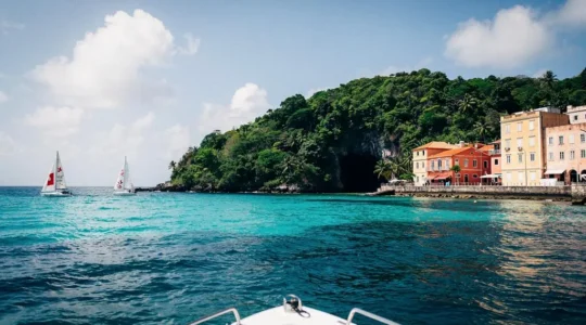 Vue symbolique d'une baie caribéenne divisée entre plage animée, crique sauvage et port historique, illustrant le choix entre les trois îles Vierges américaines