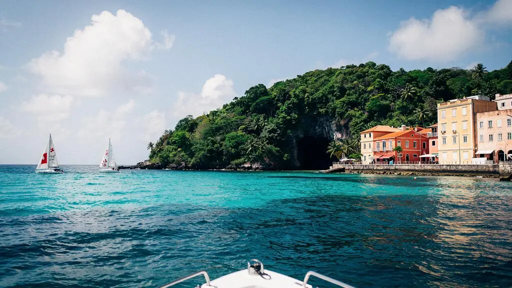 Vue symbolique d'une baie caribéenne divisée entre plage animée, crique sauvage et port historique, illustrant le choix entre les trois îles Vierges américaines