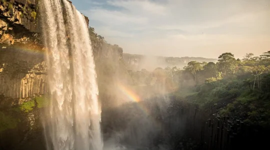 Rideau d'eau puissant des chutes Victoria enveloppé de brume dorée au coucher du soleil, vue panoramique symbolisant la force et le mystère du fleuve Zambèze