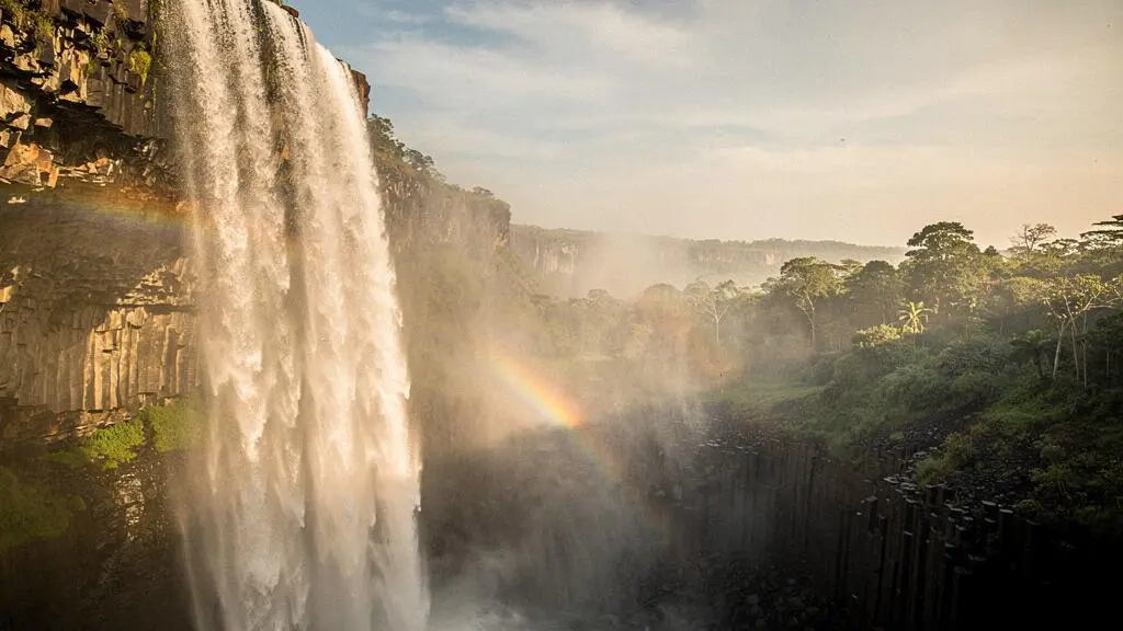 Rideau d'eau puissant des chutes Victoria enveloppé de brume dorée au coucher du soleil, vue panoramique symbolisant la force et le mystère du fleuve Zambèze